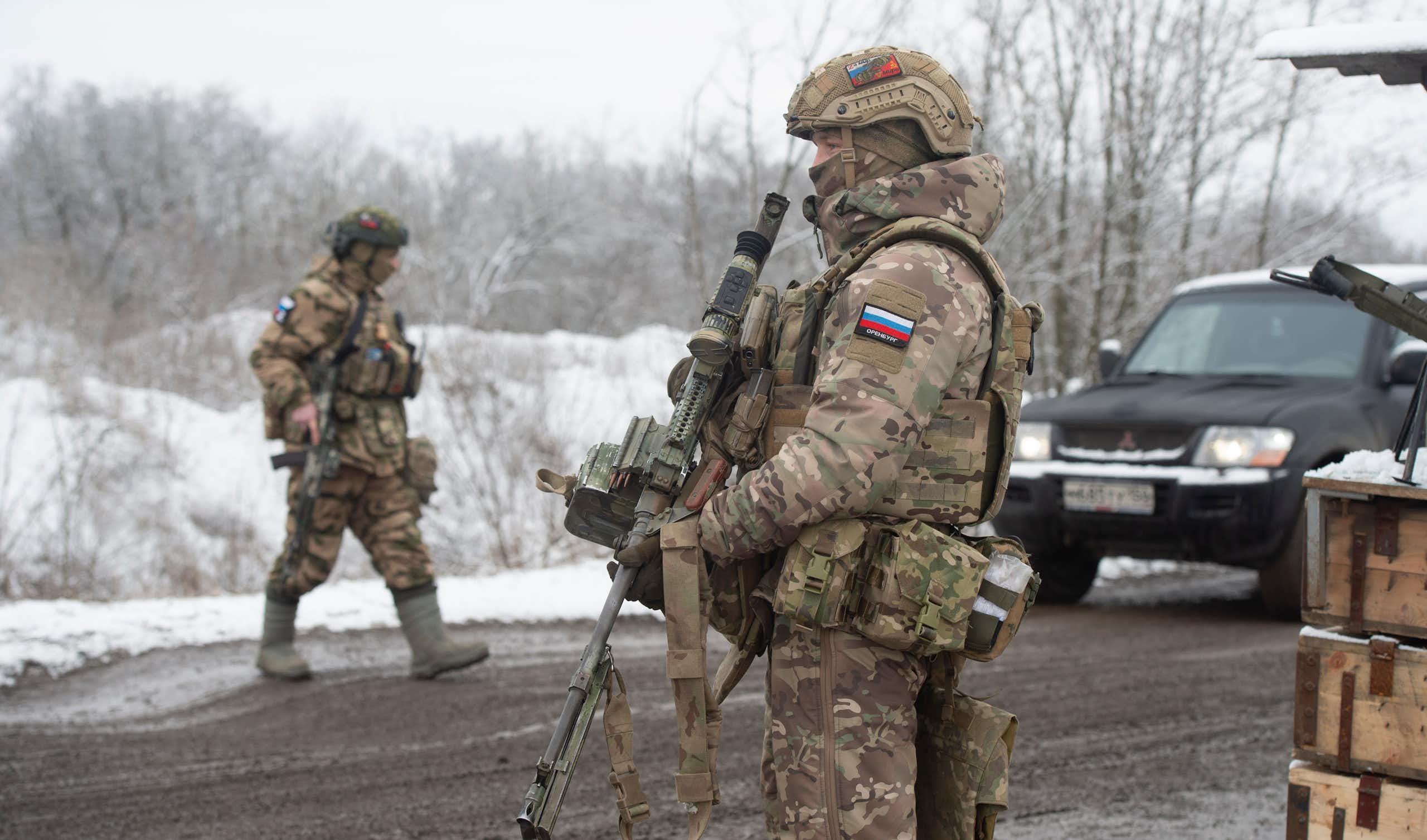 Two Russian soldiers inspect vehicles at a checkpoint in Zaporizhia