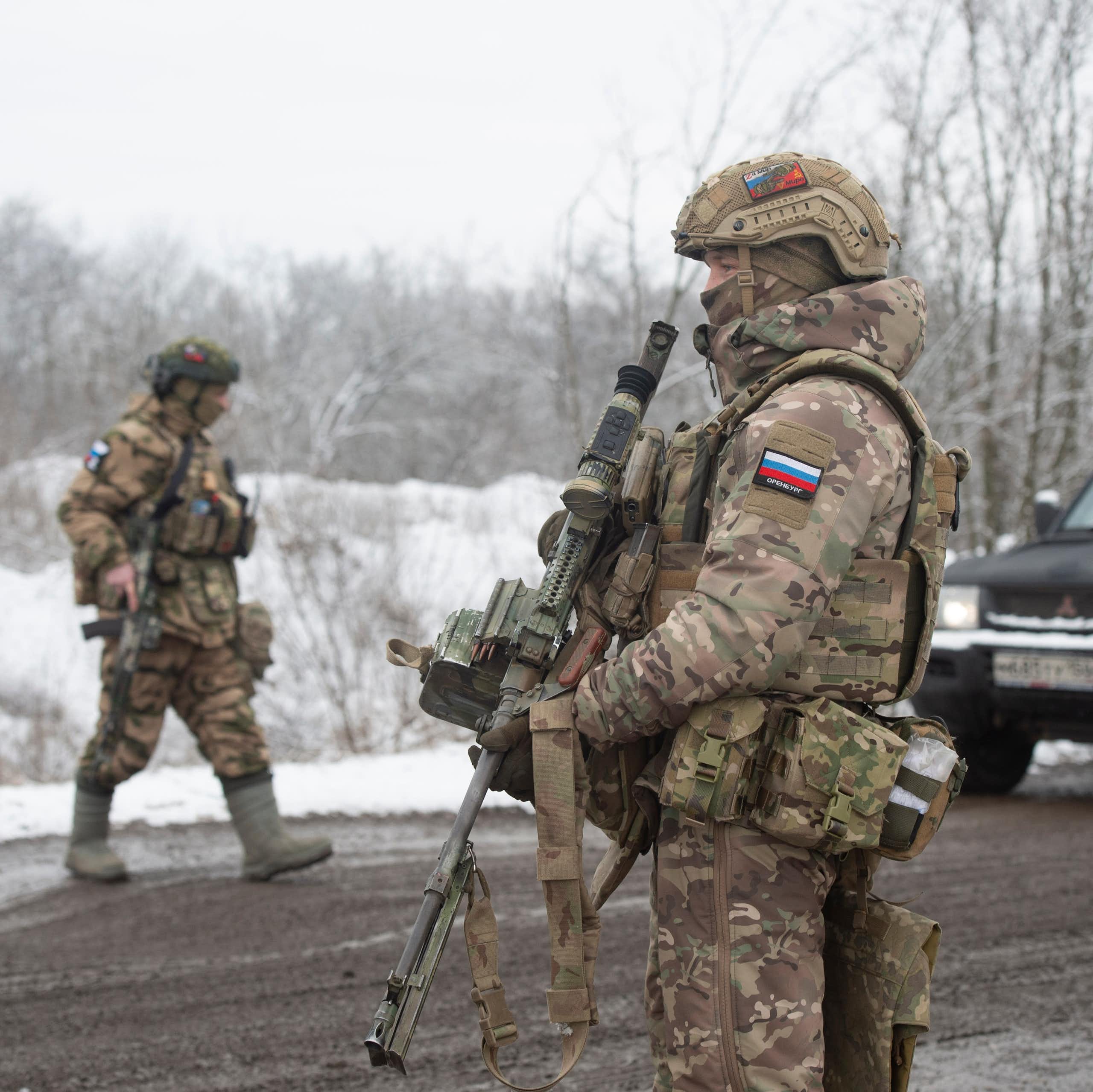 Two Russian soldiers inspect vehicles at a checkpoint in Zaporizhia