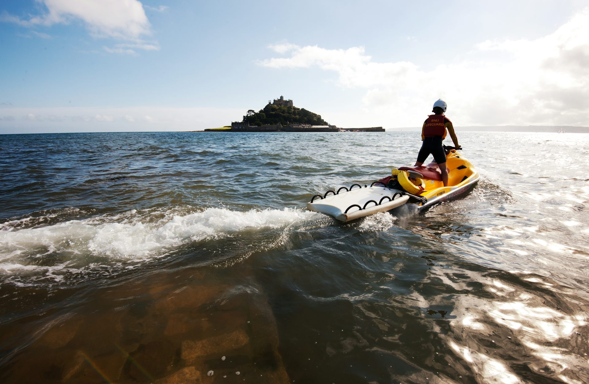lifeguard on jet ski on sea, island in background
