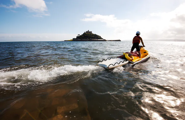 lifeguard on jet ski on sea, island in background