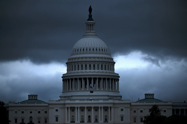 A building's dome is seen in front of dark clouds.