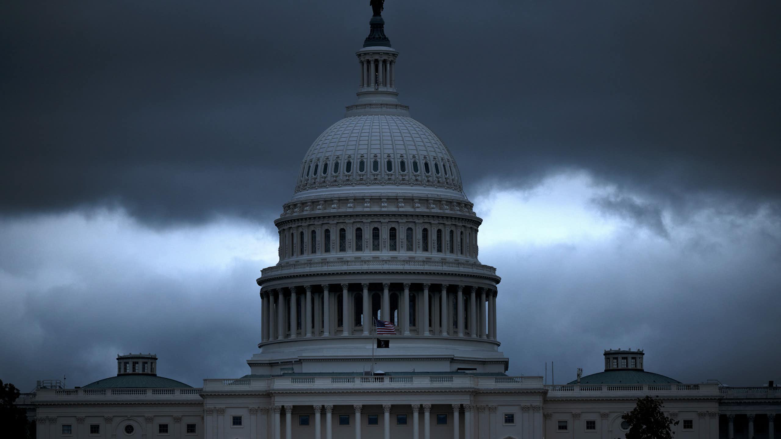 A building's dome is seen in front of dark clouds.
