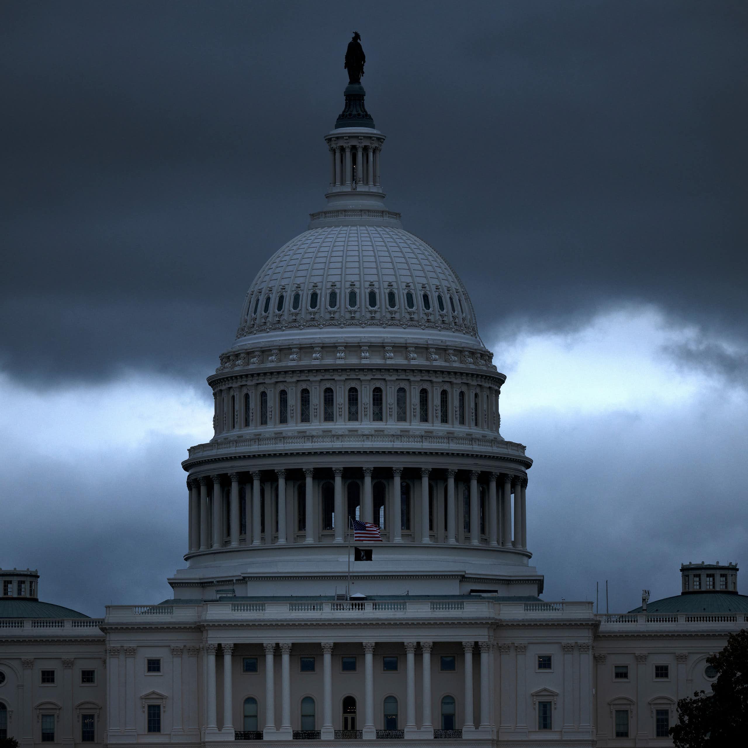 A building's dome is seen in front of dark clouds.