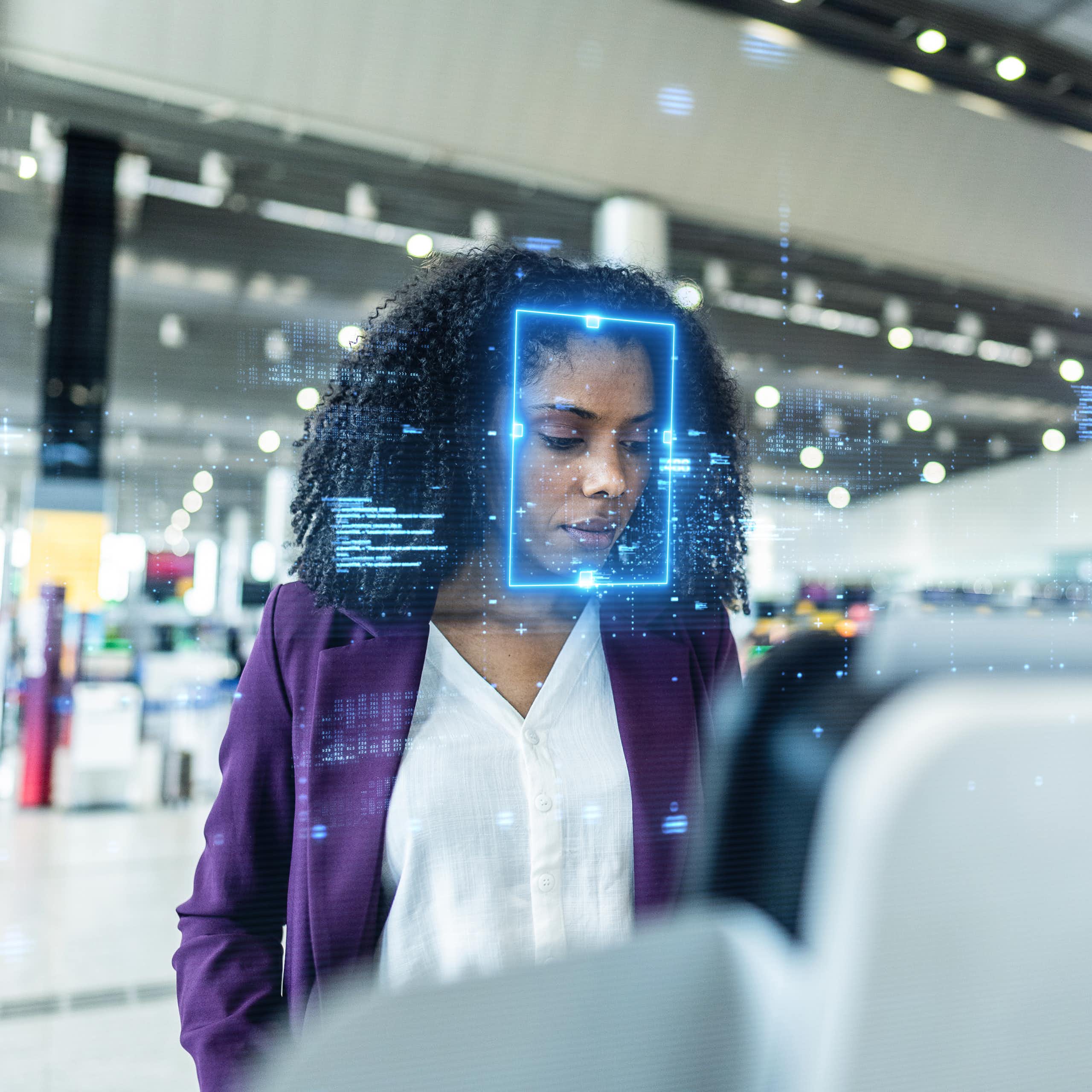 A focused businesswoman stands at an airport check-in kiosk.