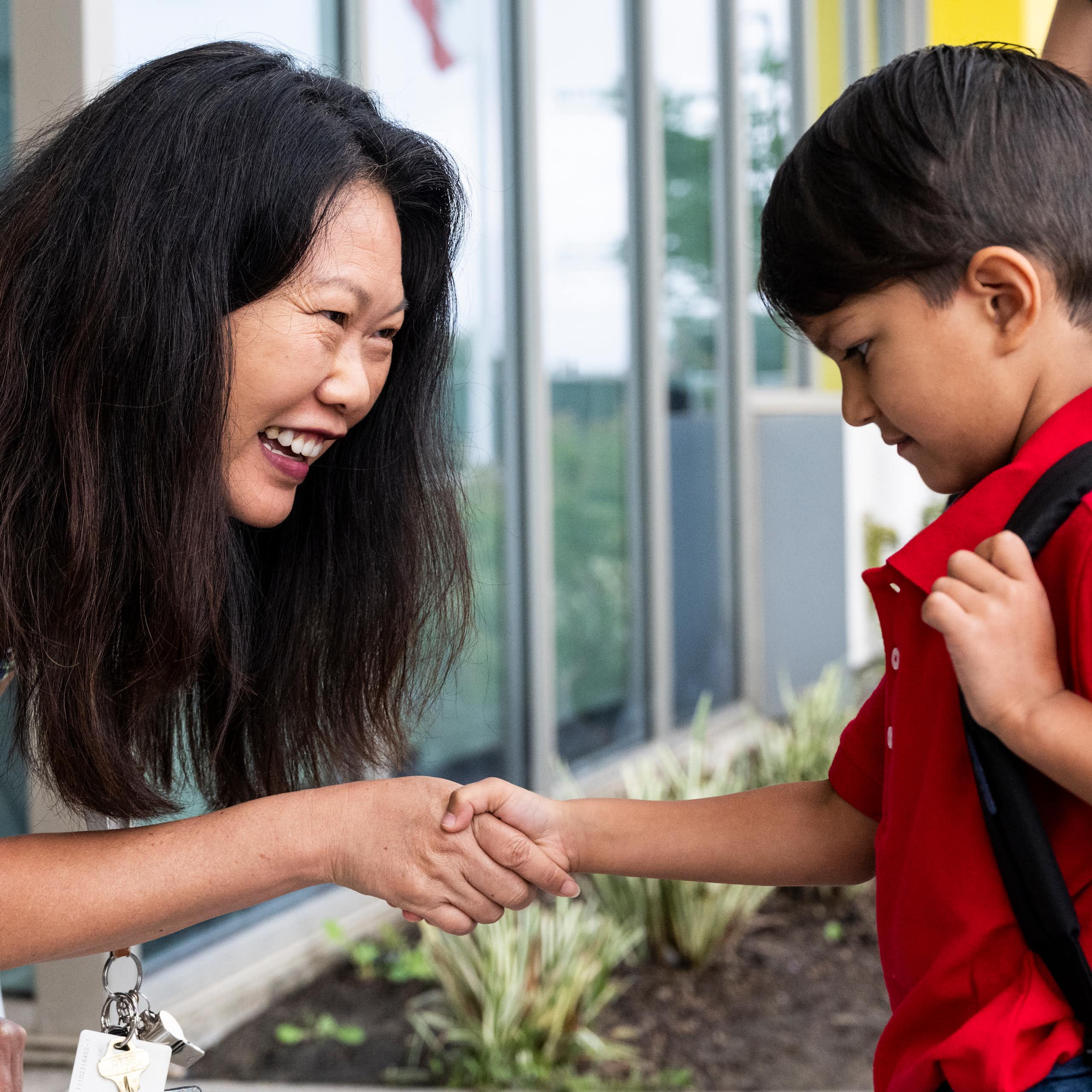 A teacher greets a young student on the first day of school.