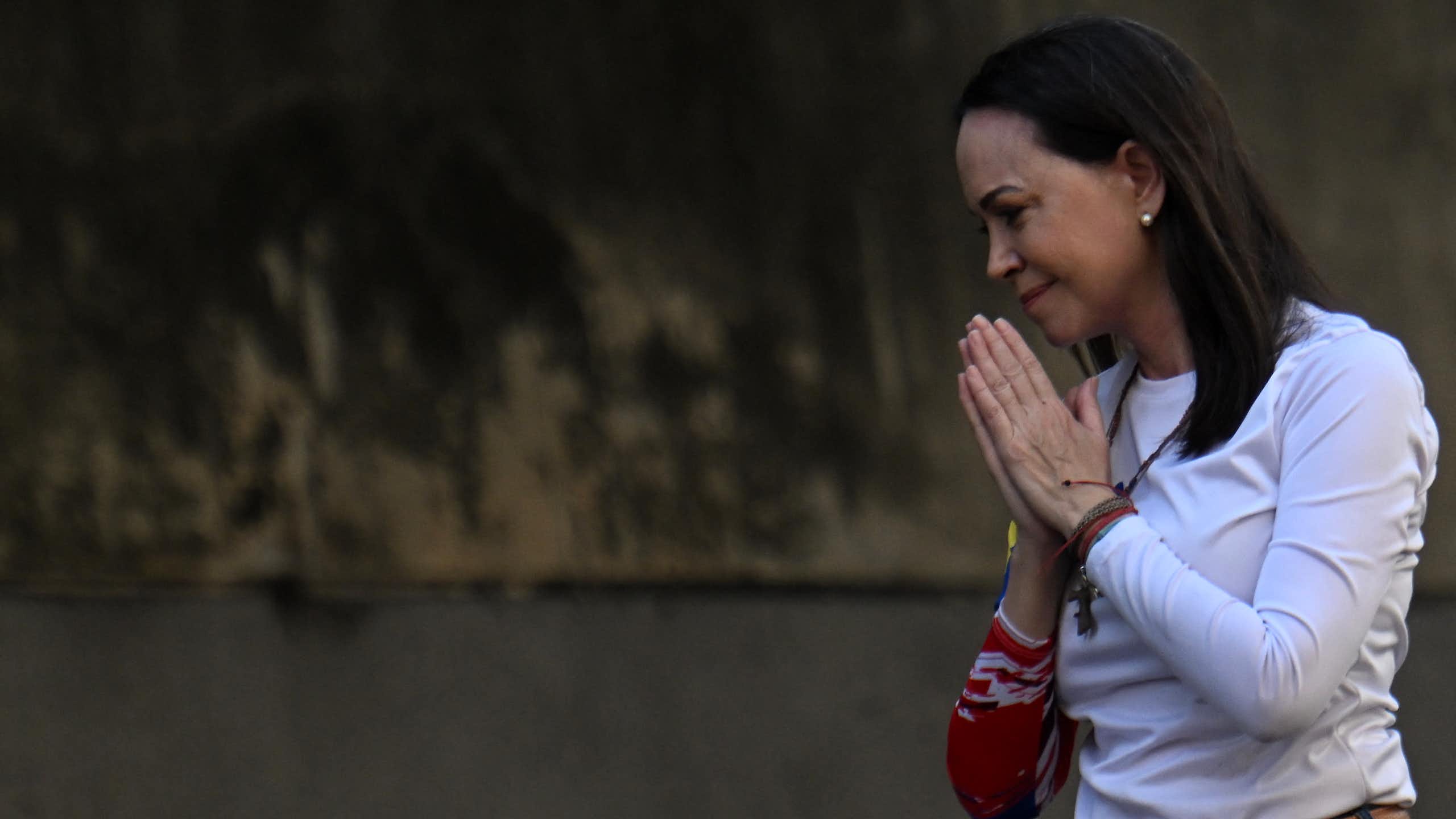 A woman. in white clasps here hands.