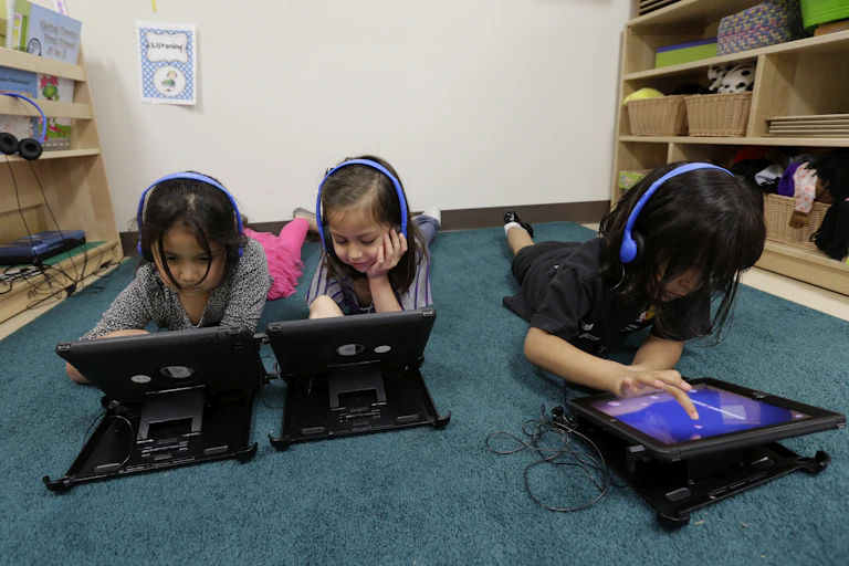 Three young students working on tablets at school.