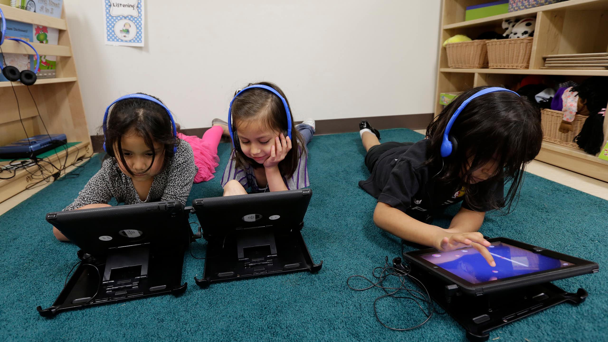 Three young students working on tablets at school.