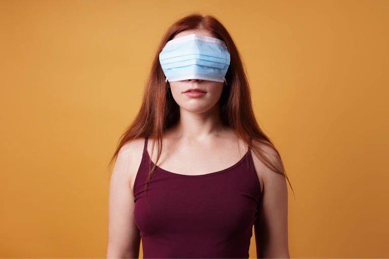 a woman stands with a mask over her eyes