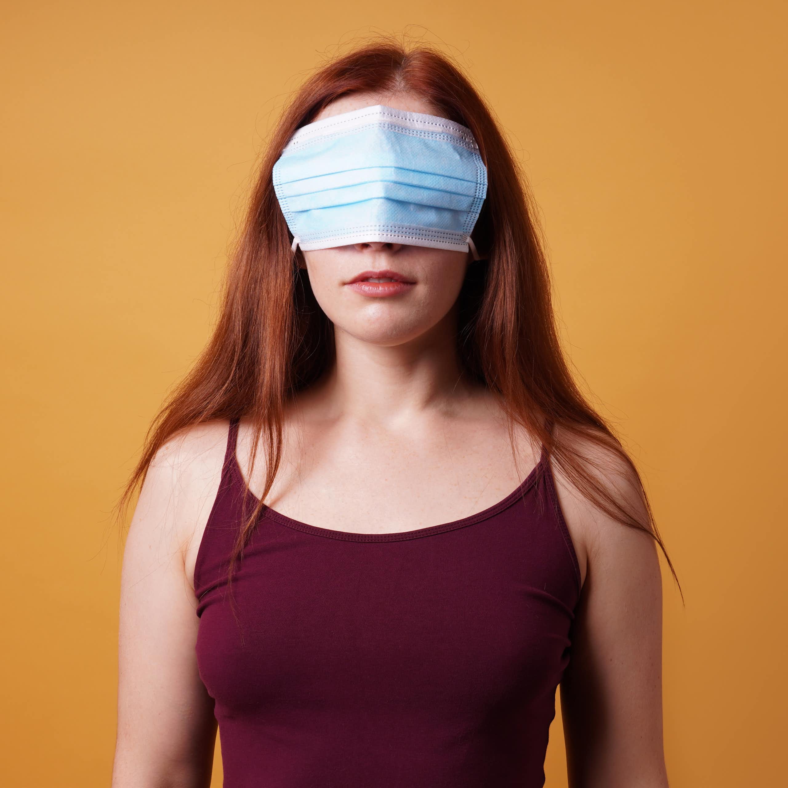 a woman stands with a mask over her eyes