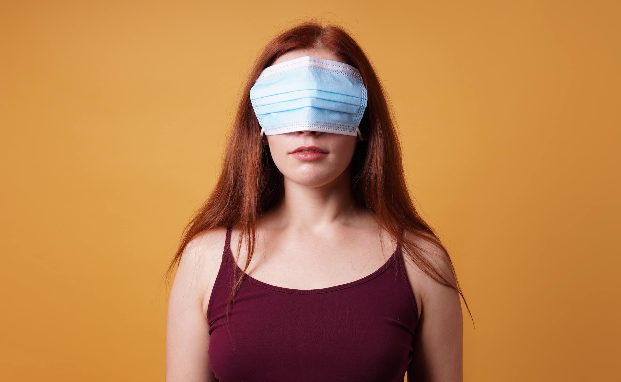 a woman stands with a mask over her eyes