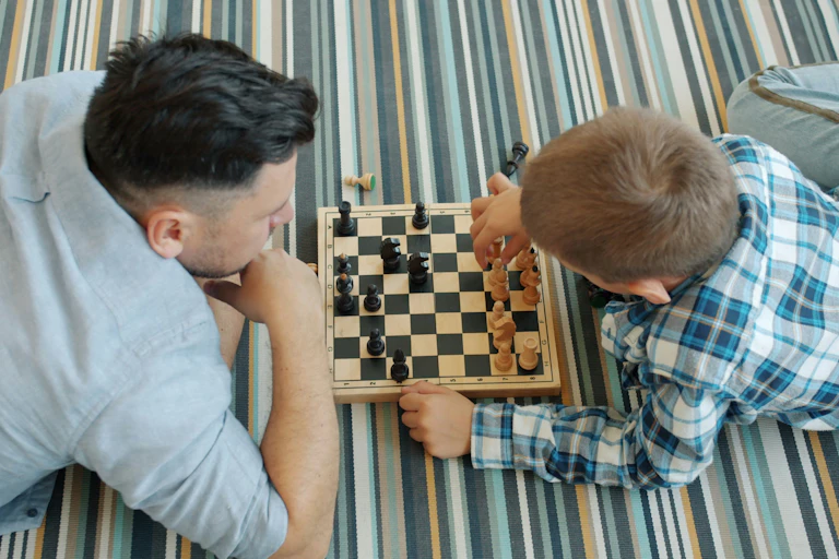 Un adulte et un enfant jouent aux échecs.