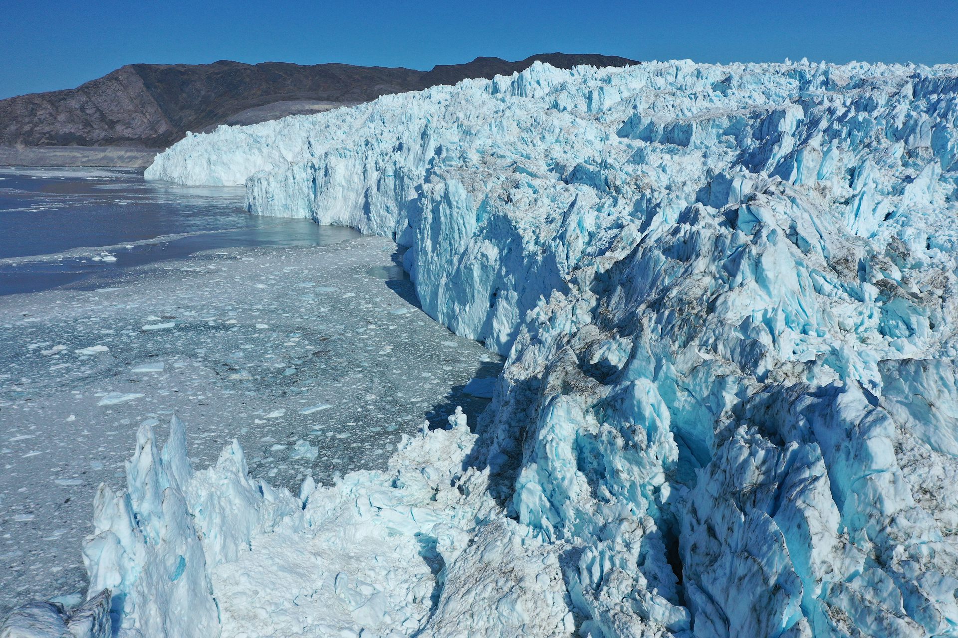 A tall glacier front seen from above shows huge chunks of ice calving off into Disko Bay.