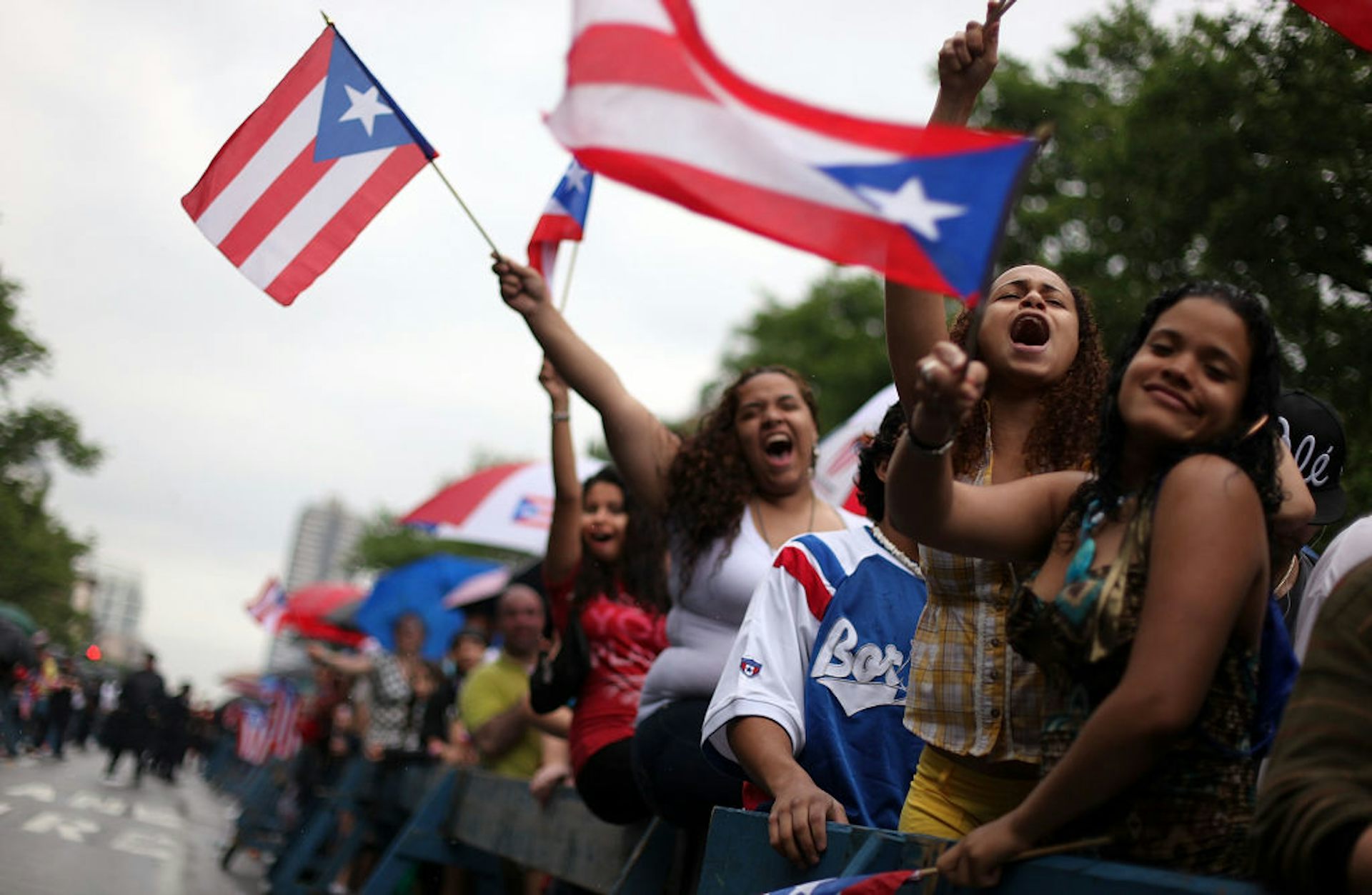Young women yell and wave red, white and blue Puerto Rican flags.