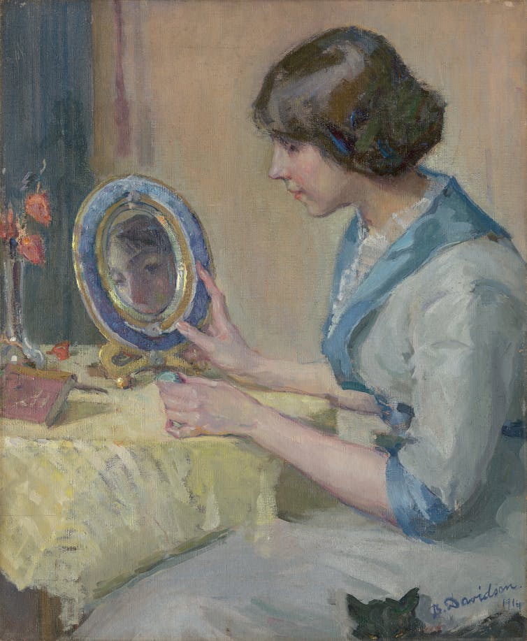 A girl looks into a small mirror.