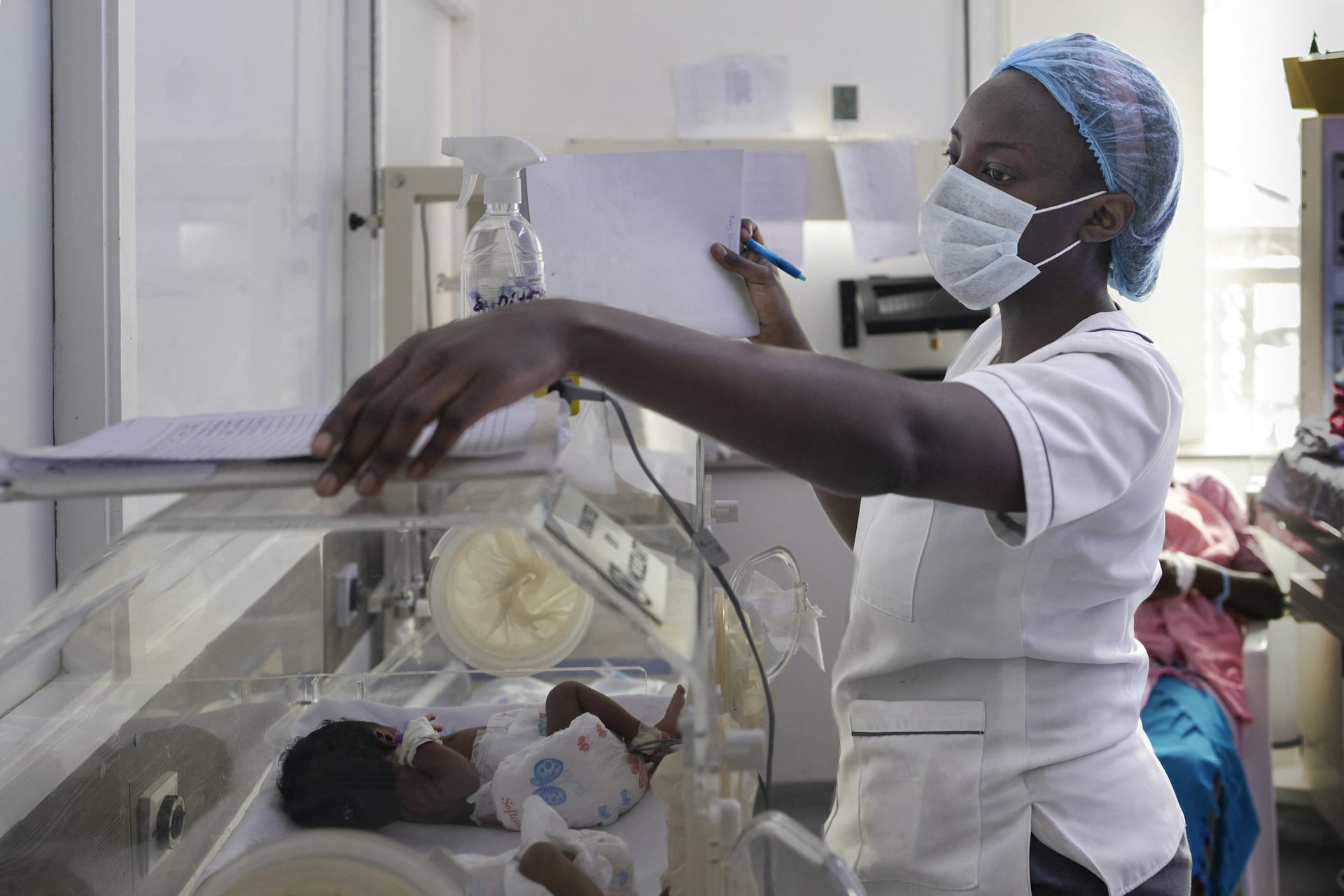 A nurse attends to a small baby in an incubator