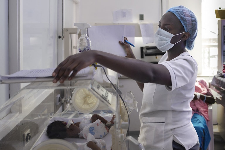A nurse attends to a small baby in an incubator