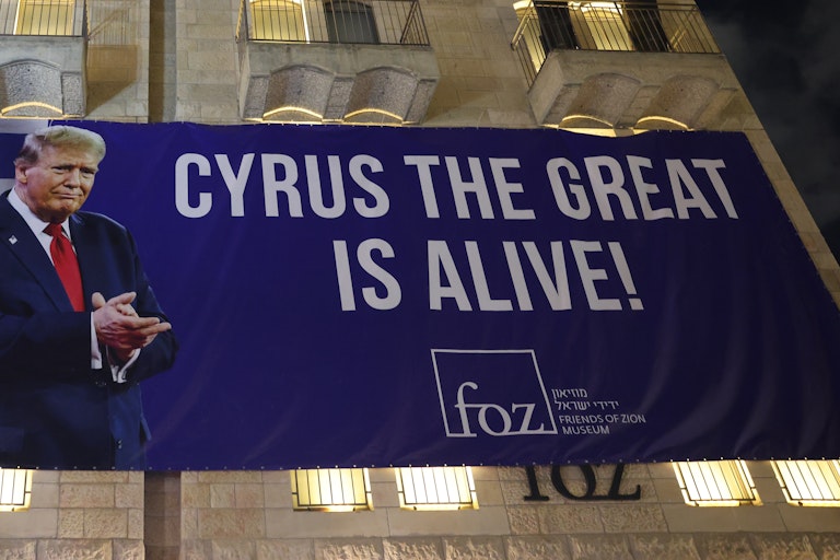 2025 年 10 月 12 日,美國總統川普訪問以色列前,耶路撒冷,工人們在一棟建築的外牆上懸掛了一條大型橫幅,感謝川普。橫幅上寫著居魯士大帝還活著。