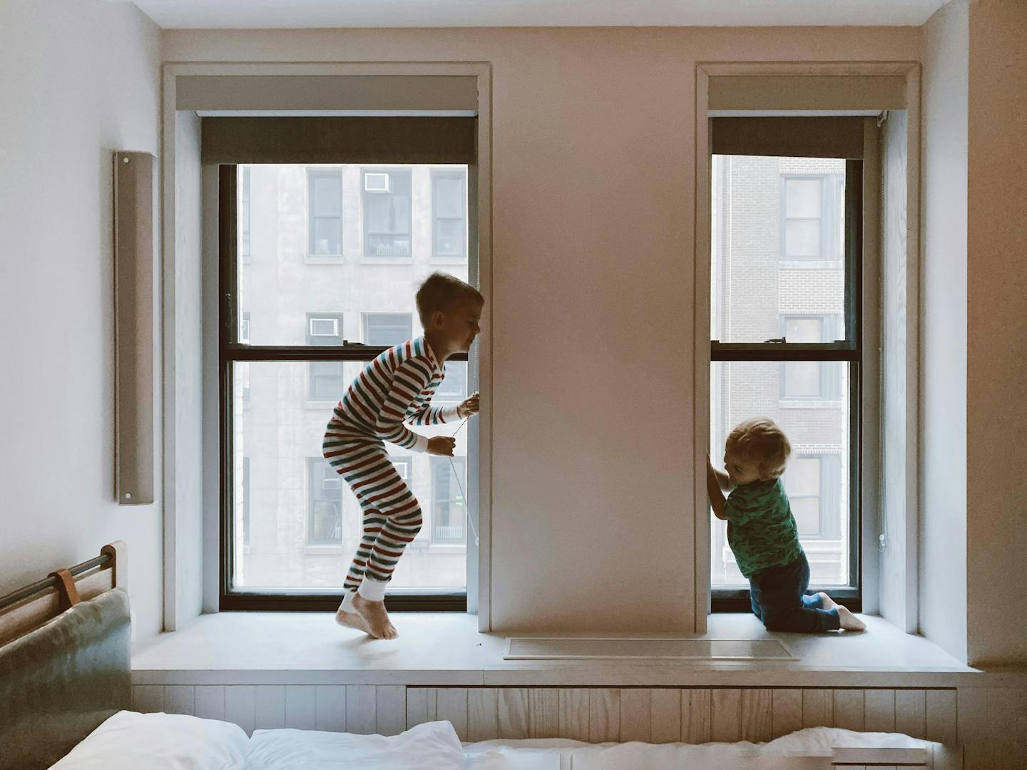 A child and a baby play on the wide windowsills in an apartment