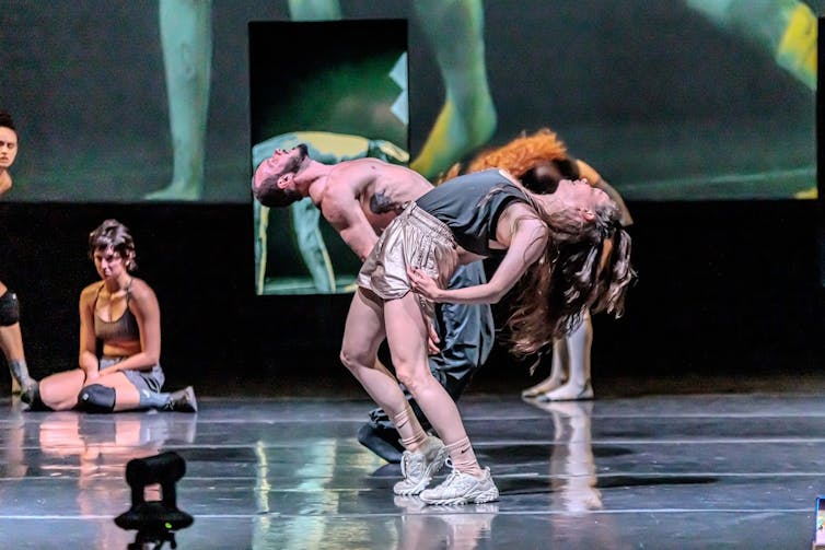 A duet, two dancers bend over backwards.