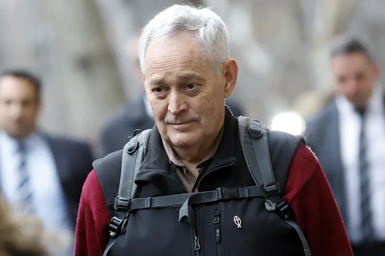 A grey-haired man with a backpack.