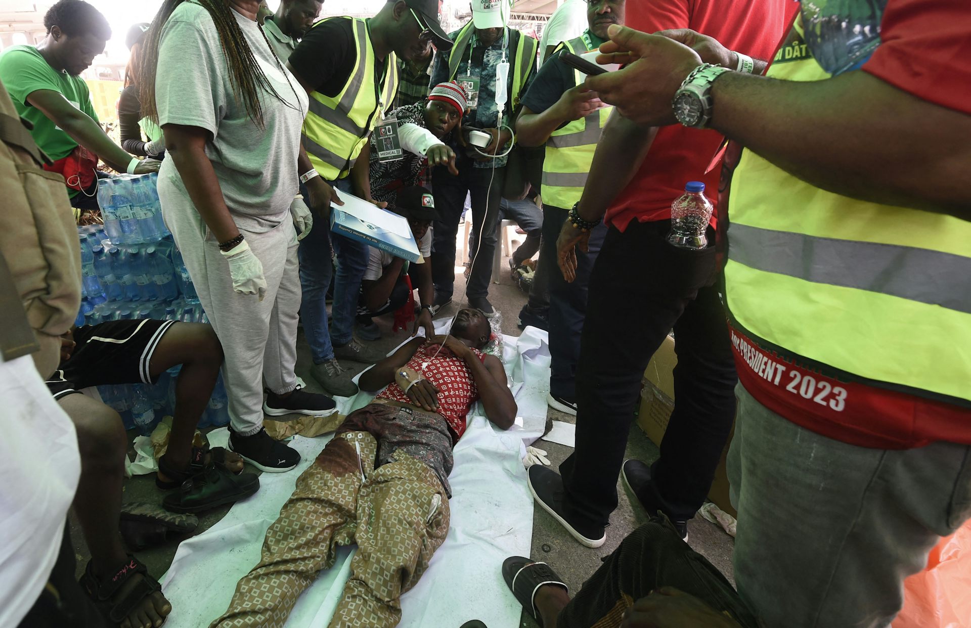 People stand around a person who is lying on the ground