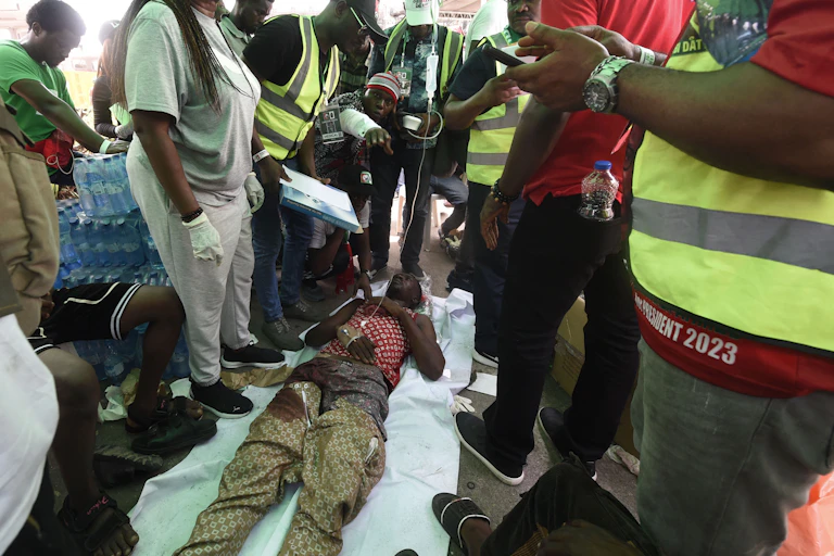 People stand around a person who is lying on the ground