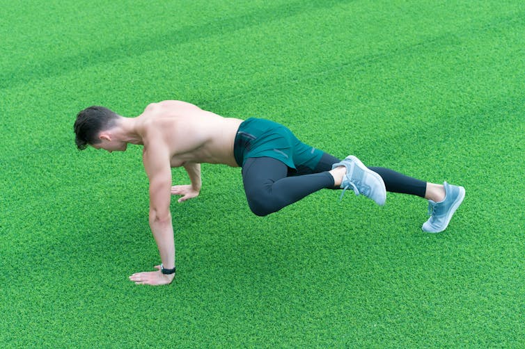 A man crawls on all fours across a turf field.