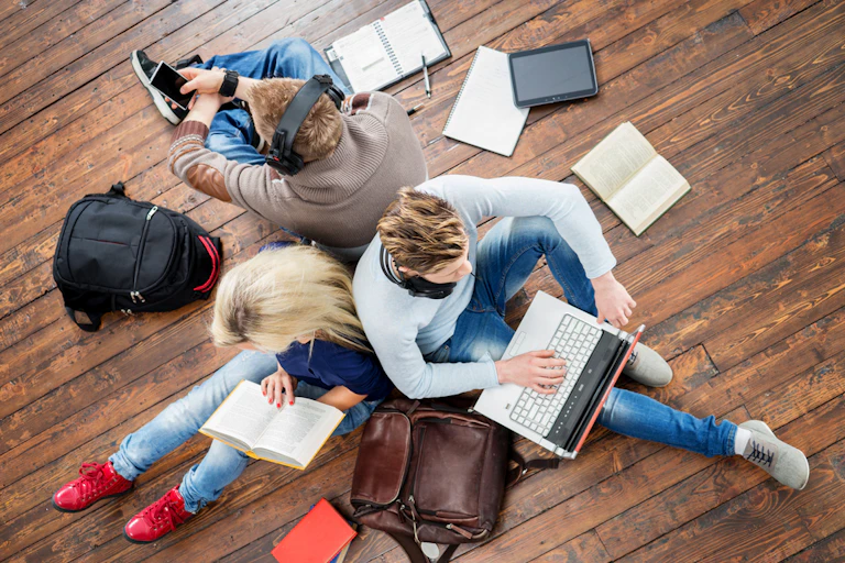 Groupe d'étudiants utilisant des smartphones, des ordinateurs portables et lisant des livres.