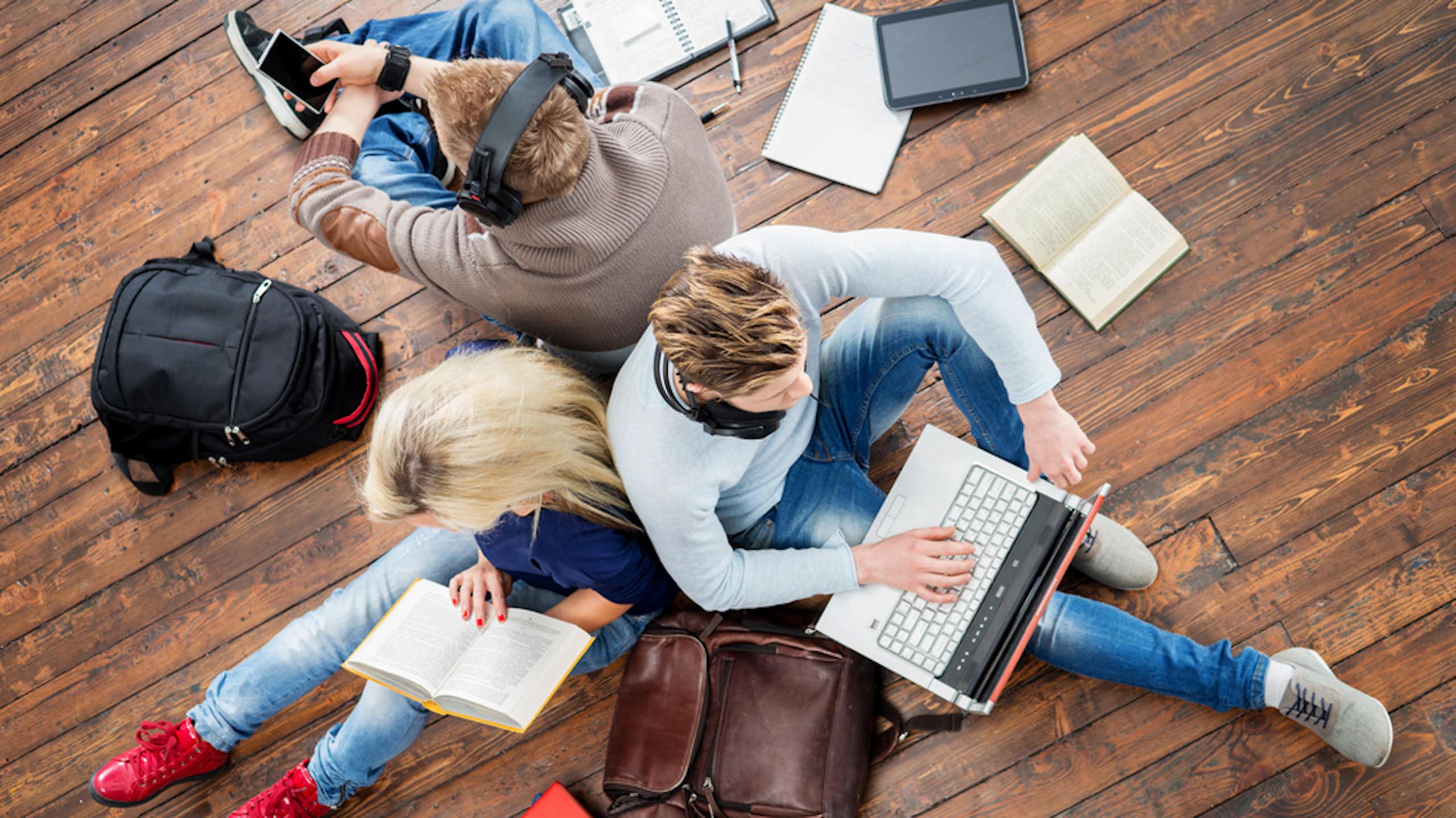 Groupe d'étudiants utilisant des smartphones, des ordinateurs portables et lisant des livres.