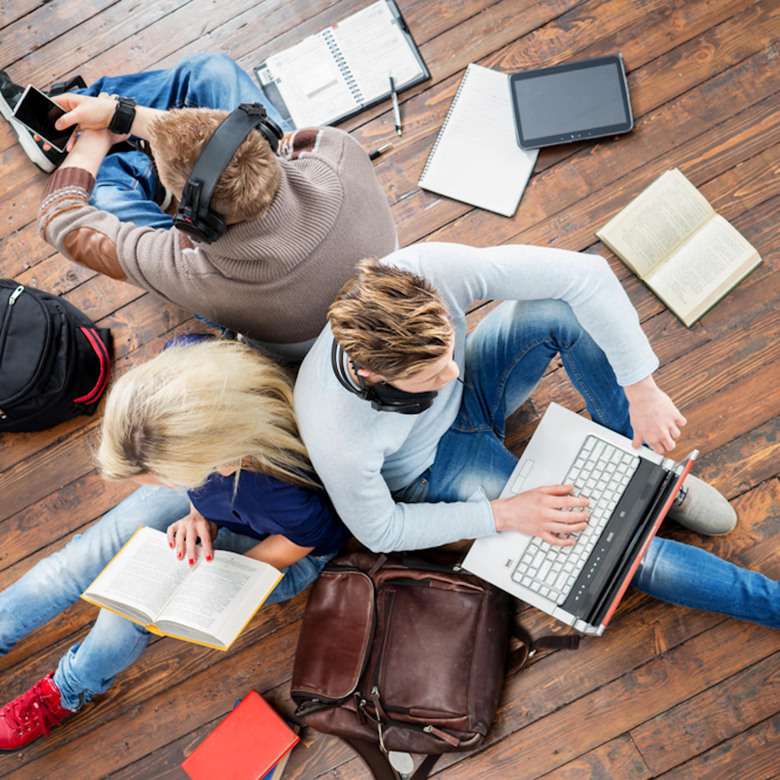 Groupe d'étudiants utilisant des smartphones, des ordinateurs portables et lisant des livres.