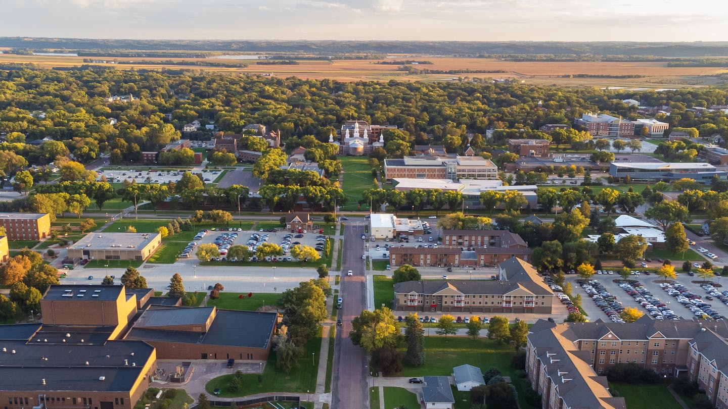 A university campus with various buildings and trees is seen from above.