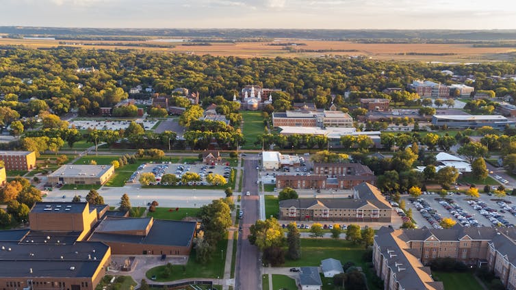 A university campus with various buildings and trees is seen from above.