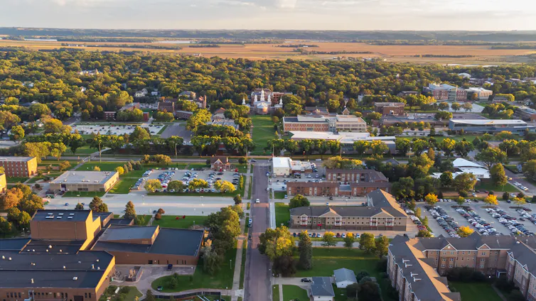 A university campus with various buildings and trees is seen from above.