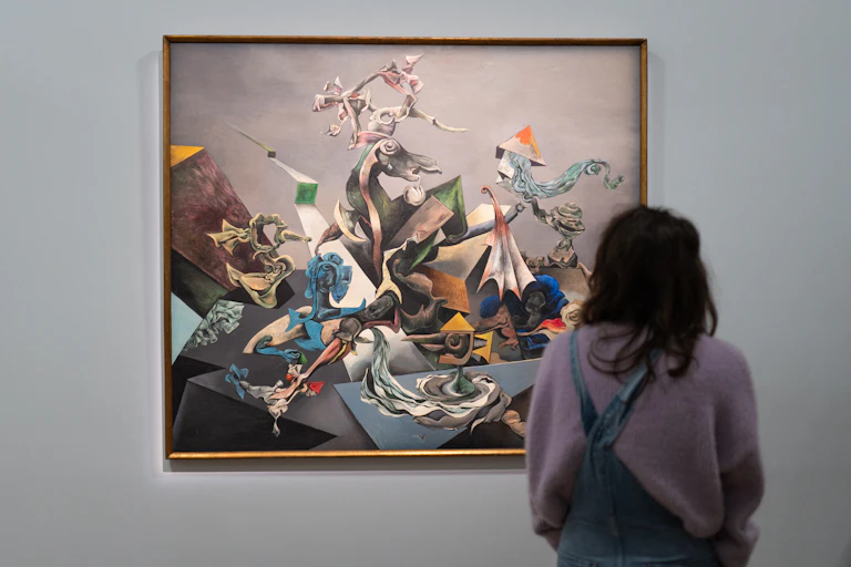 Person shown from behind standing in front of large colorful painting on gallery wall
