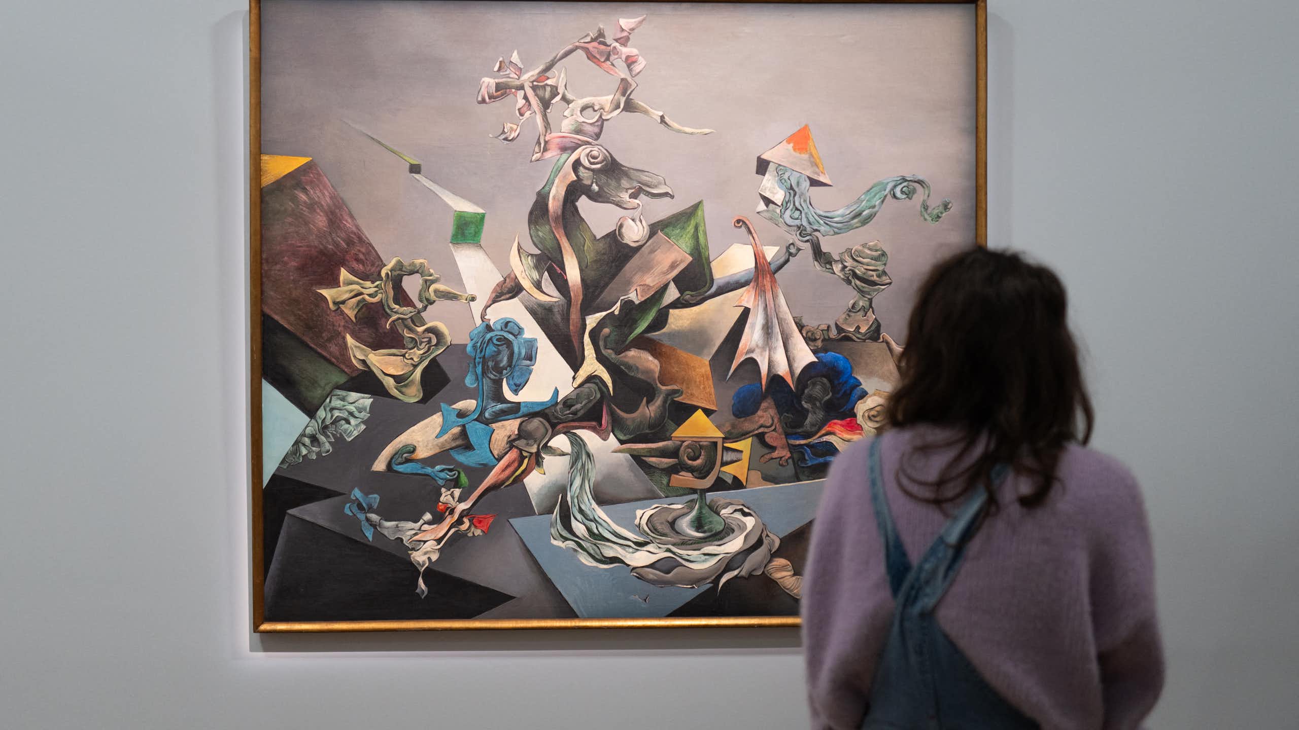 Person shown from behind standing in front of large colorful painting on gallery wall