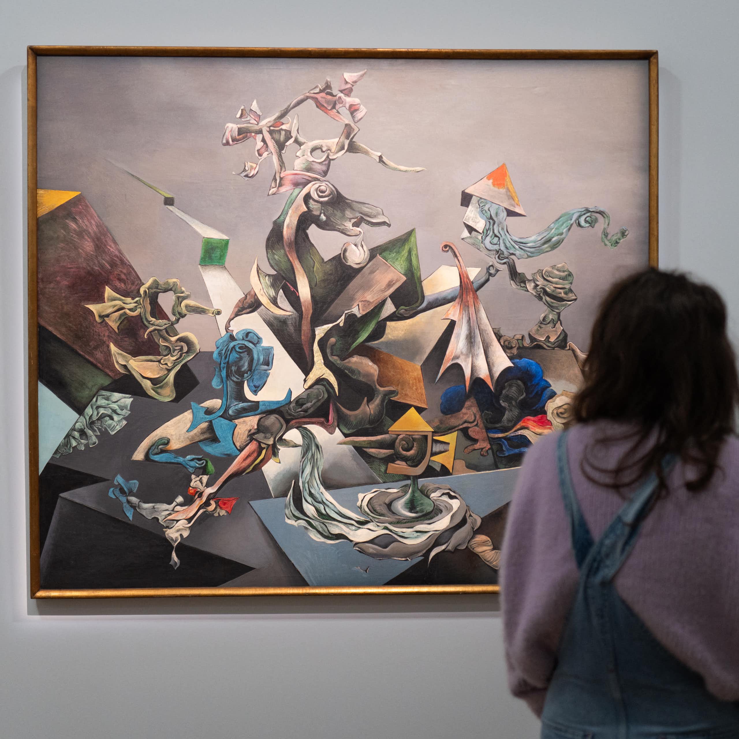 Person shown from behind standing in front of large colorful painting on gallery wall