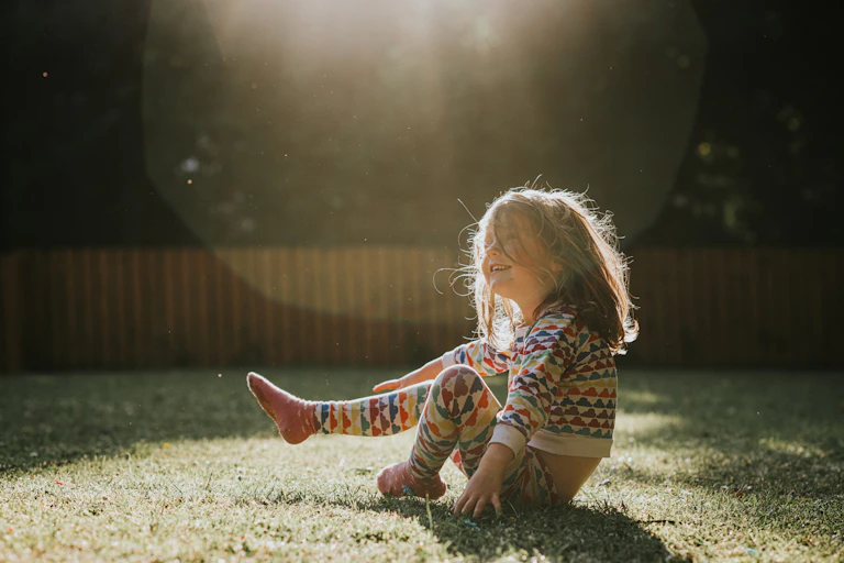 A young girl sits on grass in pyjamas