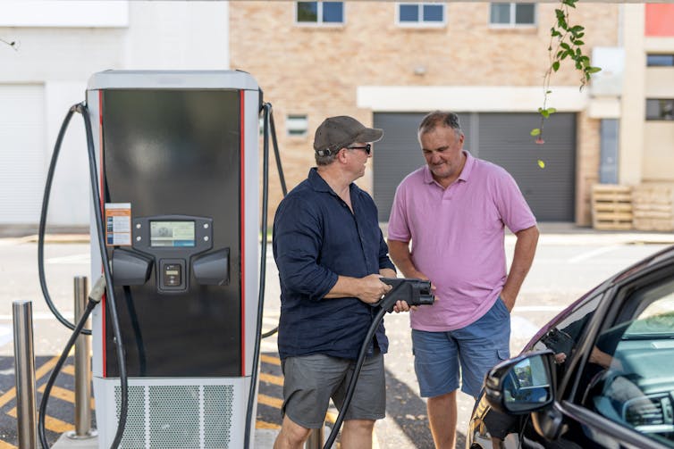Two men talking while their EV charges.