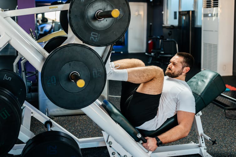 Man lifts weight on a leg press machine.