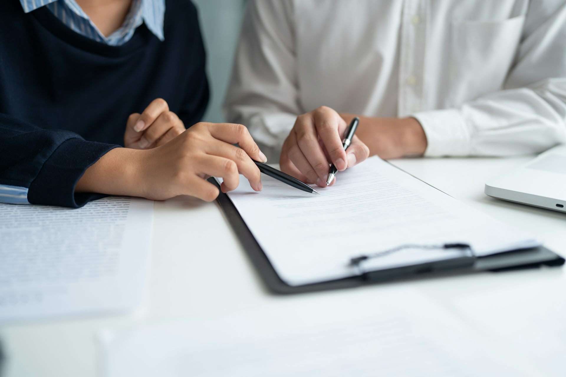 Hands holding pens over document