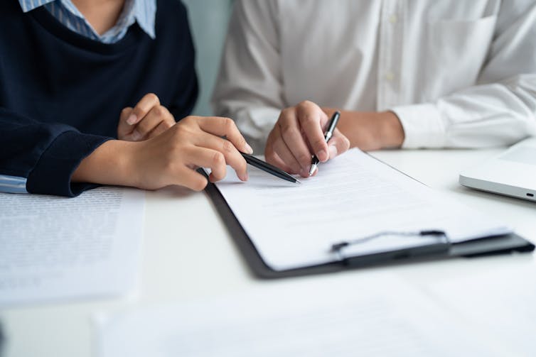 Hands holding pens over document