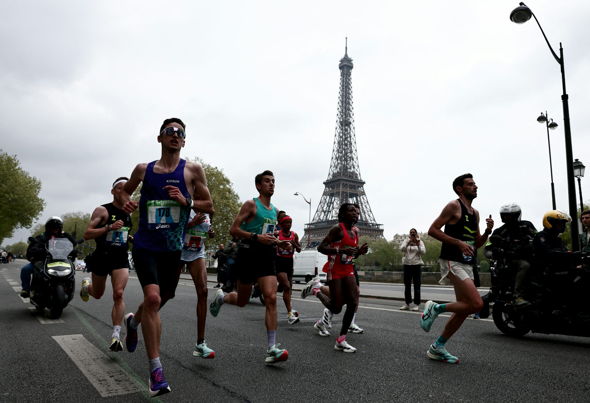 Des sportifs amateurs et professionnels en train de courir durant le marathon de Paris, avec la tour Eiffel visible dans le fond.