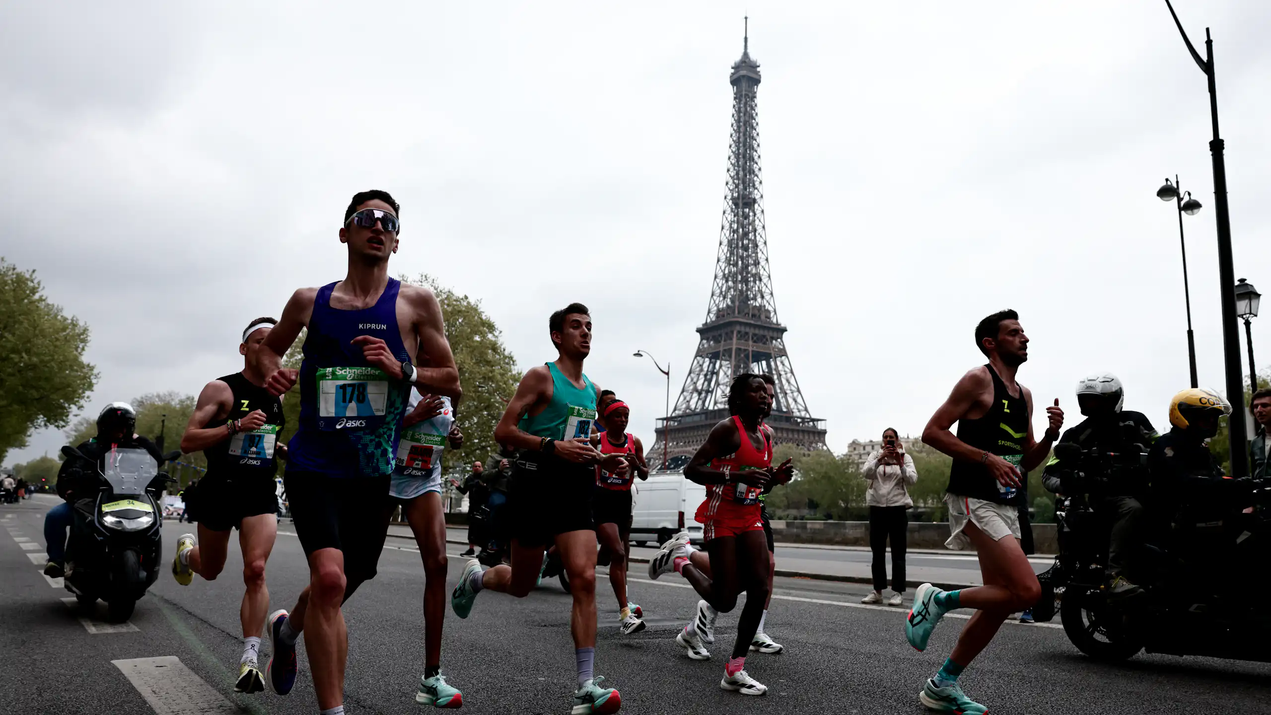 Des sportifs amateurs et professionnels en train de courir durant le marathon de Paris, avec la tour Eiffel visible dans le fond.