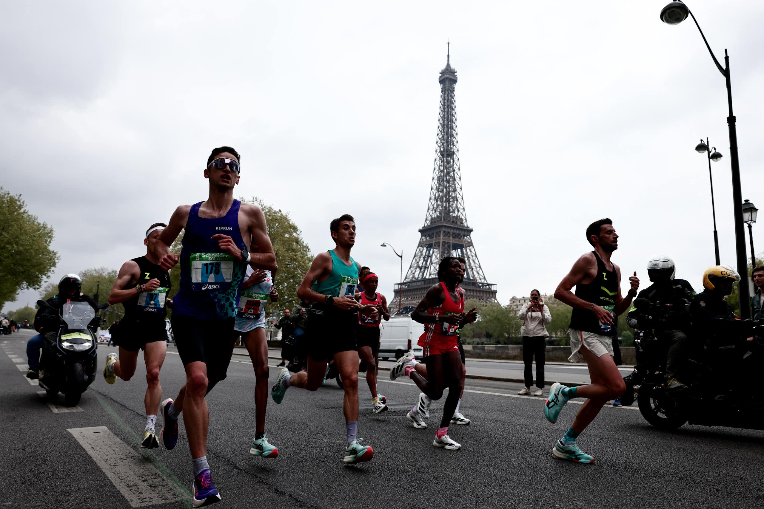 Des sportifs amateurs et professionnels en train de courir durant le marathon de Paris, avec la tour Eiffel visible dans le fond.