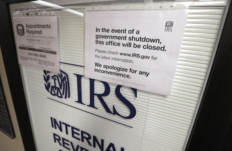 A sign on a door warns people that during a partial government shutdown, the IRS office will be closed.