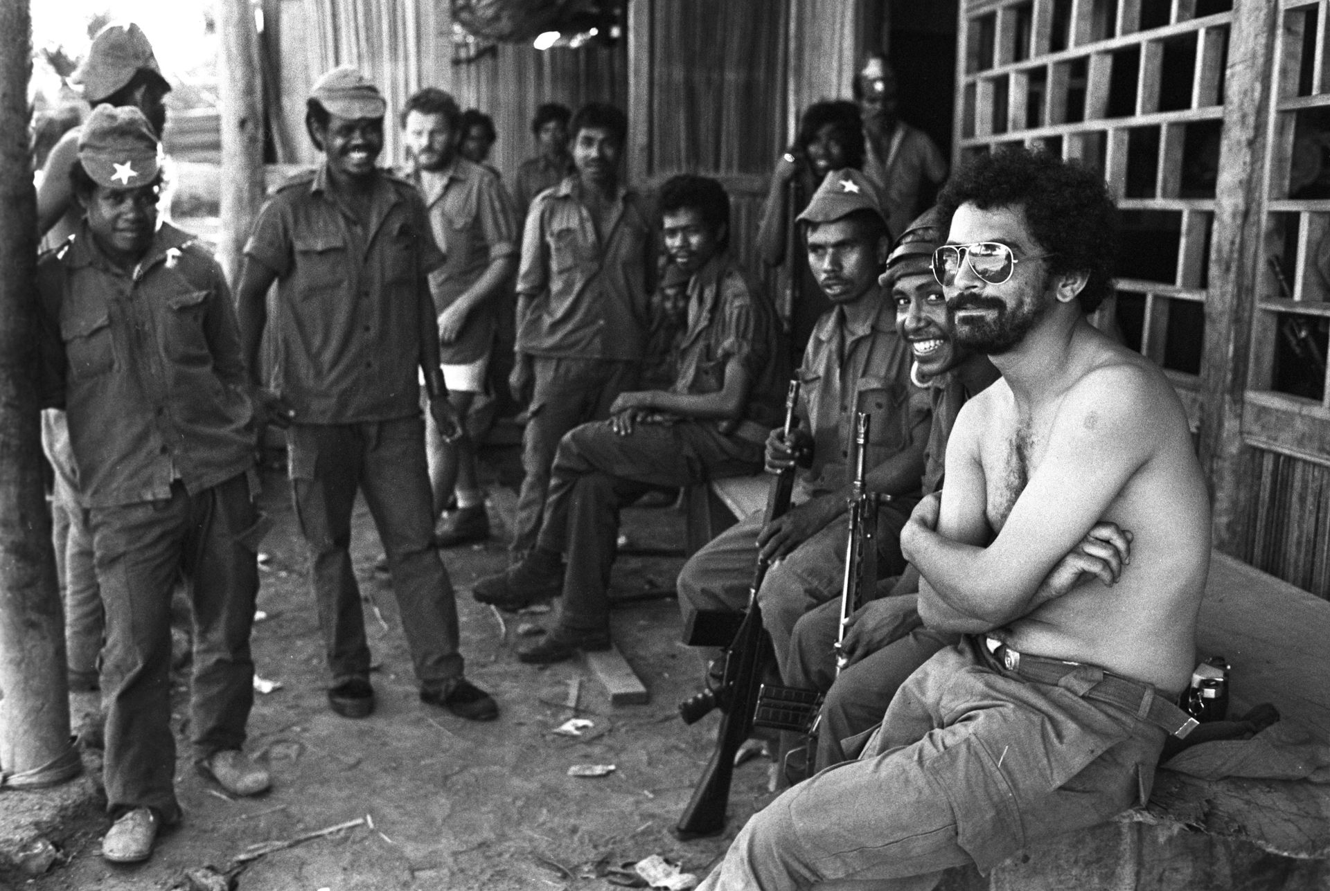 A black and white photo of a group of soldiers and a young shirtless man