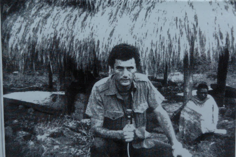 A black and white image of a man in the 1970s holding a microphone