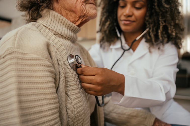 Doctor holding stethoscope to patient's chest