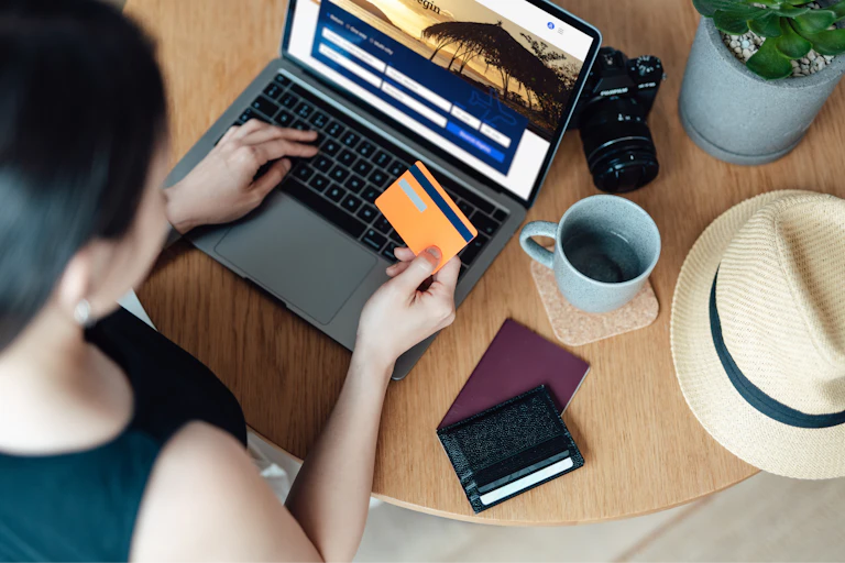 young woman booking flight ticket online using laptop, making payment with credit card